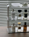 Modern Aira stainless shelf displaying perfume bottles near window blinds.