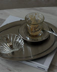 Matte Stainless Steel Oval Plate used as a tray with a coffee cup, glass shell dish and spoon