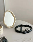 Nordic cloud-shaped vanity mirror in cream and black with accessories, on a white table, size 27x20cm - 10.6x7.85 inches, free shipping.