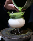 Pouring matcha into the Lune Sculptural Goblet over milk