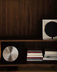 Bauhaus Aura Bedside Lamp on a bookshelf beside a row of books