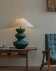 Elegant ceramic pot table lamp with linen shade on modern wooden side table, accentuating cozy living room decor.