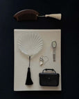 Lumière Shell Glass Dish with the metal comb and a watch on a dark surface