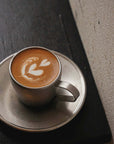 Vintage inox cup and saucer with latte art on a wooden table, made of 18-8 stainless steel from Japan.