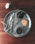 Stainless steel cutlery with crackers and drink on a wooden table featuring VINTAGE INOX Baguette Classic Series design.