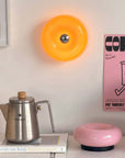 Orange Halo Touch Lamp lit on a shelf above a coffee pot and a pink lamp