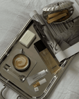 Spring Bundle: Signature tray with Venice cup, shell trinket case, perfume and a book on a bed