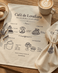 Café de LoveÉcru cotton napkin with printed menu on a table with coffee