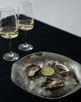 Sculpted Stainless Steel Bowl with oysters on ice beside two glasses of white wine