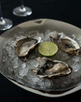 Sculpted Stainless Steel Bowl with oysters on ice and a wine glass