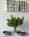 Stello Countertop Grid Shelves on a wall above a table with a vase and steel bowls