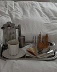 Signature Serving Tray with a French press, cups, toast rack and eggs on a bed