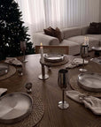 Stainless Steel Champagne Flutes on a table set with steel plates by a Christmas tree