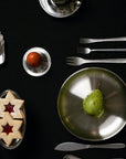 Stainless Steel Egg Cups on a breakfast table with steel plates and cutlery, top view