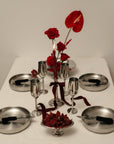 Noir Steel Plates set around a vase of red flowers on a white table