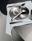 Set of Six Stainless Steel Plates set with cutlery on a white napkin