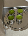 Stainless steel spherical cups with green drinks on a silver tray, showcasing elegance and style for serving beverages.