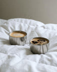 Two Spherical Cups with coffee and ice on a white bed