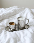 Milano Duo Set with two coffees on the oval steel tray, on a white bed