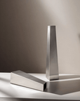 Arco Stainless Steel Vase, large, lying beside a small one on a white surface