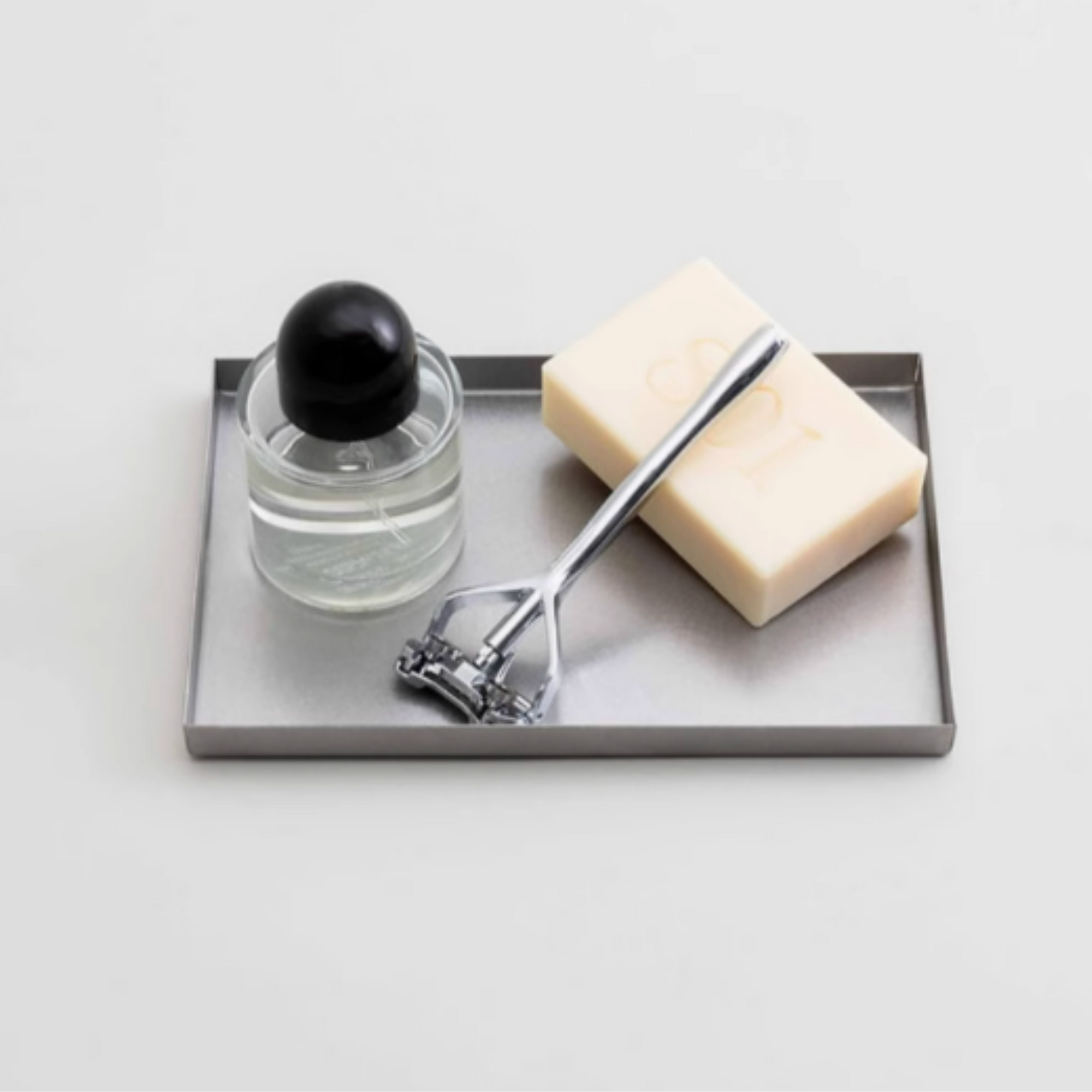 Forma Steel Catchall Tray holding soap and a roller, showcasing its sleek design and brushed stainless steel finish.