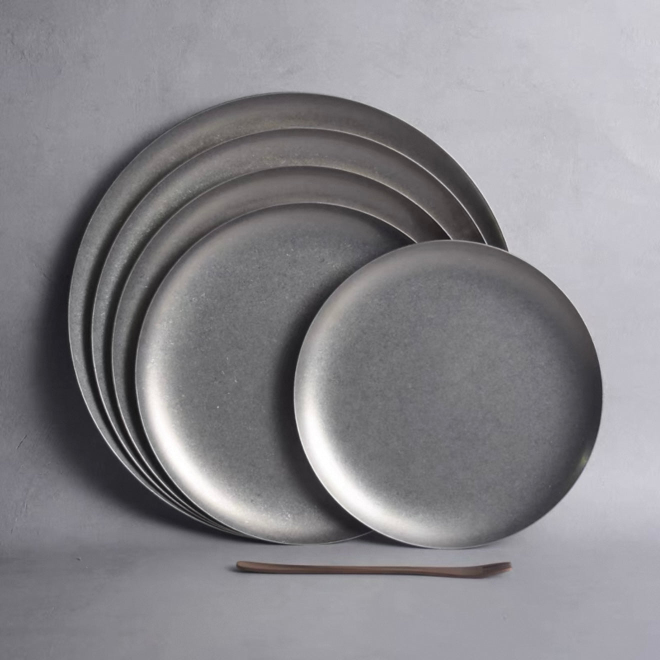 Set of matte-finished stainless steel Hakone Plates in gray tones, showcasing minimalist design for elegant dining.