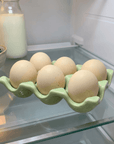 Green Ceramic Wavy Egg Tray with eggs on a glass fridge shelf