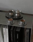 Vintage INOX stainless steel cup and saucer set with teapot and creamer on a shelf with books.