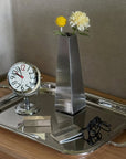 Arco Stainless Steel Vase with a single flower on a mirror tray with a clock