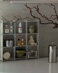 Stello Countertop Grid Shelf on a counter with coffee tools, a French press and a branch