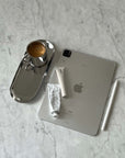 Minimalist steel tray with coffee cup next to tablet and stationery on marble surface.