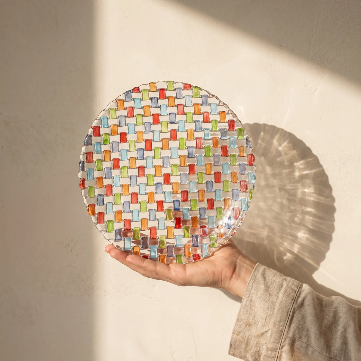 Tessera hand-painted mosaic plate 28.2 cm held against a sunlit ivory wall