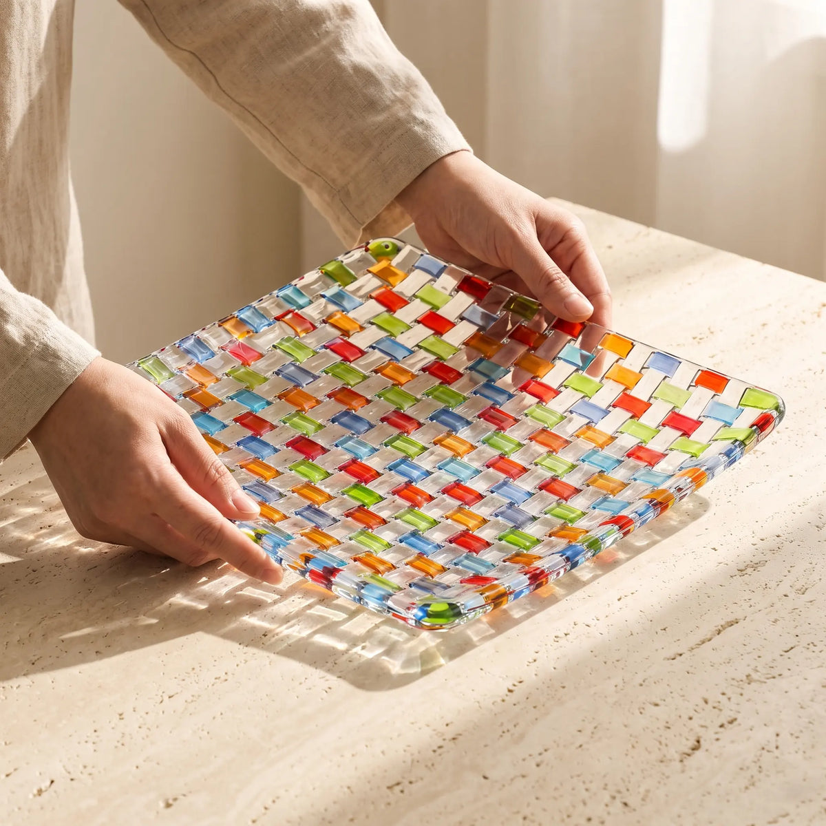 Hands placing the Tessera square platter on a stone table