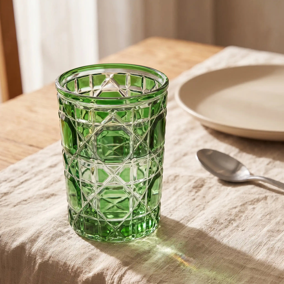 Green Vetra Lattice glass filled with water on a linen tablecloth