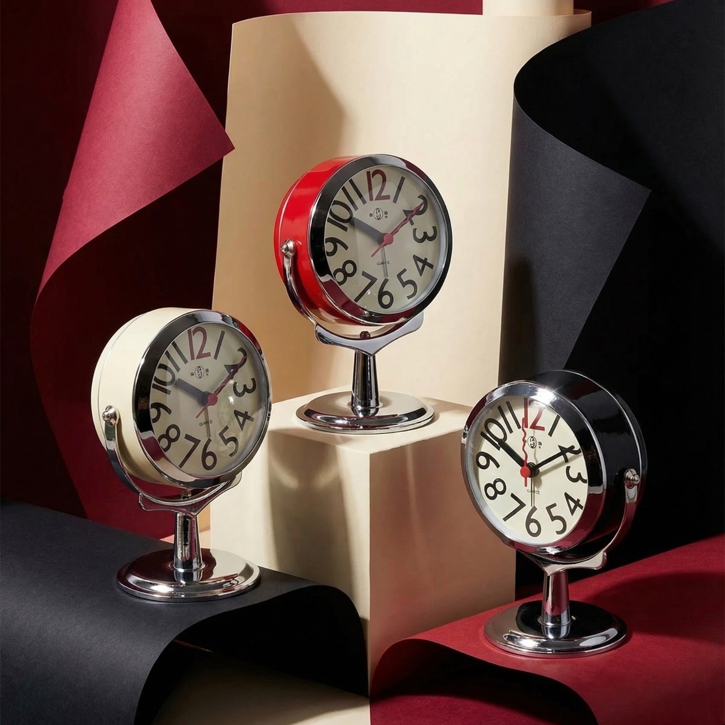 Three decorative table clocks with a red, white, and black color scheme on a colorful background.