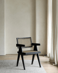Chandigarh chair made of African teak and rattan, featuring wabi-sabi design and Buddha-inspired carvings in a minimalist setting.