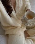 Woman in cozy cream outfit holding Rinka Mug & Plate Set with coffee, showcasing elegant porcelain design and handmade texture.