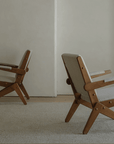 Two Scissors Chairs made of imported teak wood with S-shaped frames and armrests, showcasing a minimalist lounge design in a neutral room.
