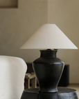 Short Neck Table Lamp with clay base and linen shade on a side table, offering warm, adjustable light for cozy home decor ambiance.