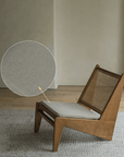 Kangaroo Chair with rattan and solid wood frame, featuring a Z-shaped design and close-up of fabric texture, on a wooden floor.