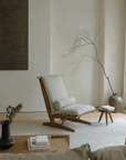 Nakajima George Reclining Chair in a minimalist living room, showcasing its teak wood frame and hand-woven rattan design.