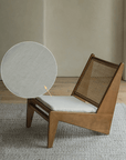 Kangaroo Chair with rattan and solid wood in Z shape design, featuring a textured cushion and curved backrest on wooden flooring.