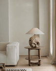 Stylish carved table lamp made from recycled wood with unique patterns, on a wooden side table in a cozy, minimalist living room setting.