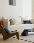 Modern living room featuring a Kangaroo Chair with rattan and wood design, placed beside a rustic coffee table and cream sofa.