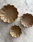 Three Rinka bowls in varying sizes with a flower shape on a marble surface, part of the Kaneko Kohyo porcelain collection.