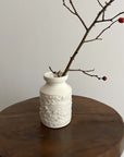 White vase by Yoshida Pottery with nature-inspired patterns on a wooden table, showcasing minimalist elegance and artisanal design.