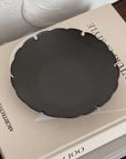 Yukiwa Plate by Yoshida Pottery displayed on a book, showcasing elegant nature-inspired design in dark ceramic.