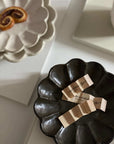 Elegant black and white scalloped plates with tea packets, showcasing modern tableware design.