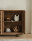 Medieval sideboard cabinet with open wooden doors revealing shelves, featuring rustic pottery and books for a vintage touch.
