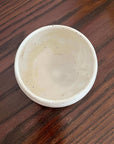 Ivory porcelain matcha bowl on wooden surface, showcasing its rounded form and calm colors, perfect for enjoying Japanese matcha culture.